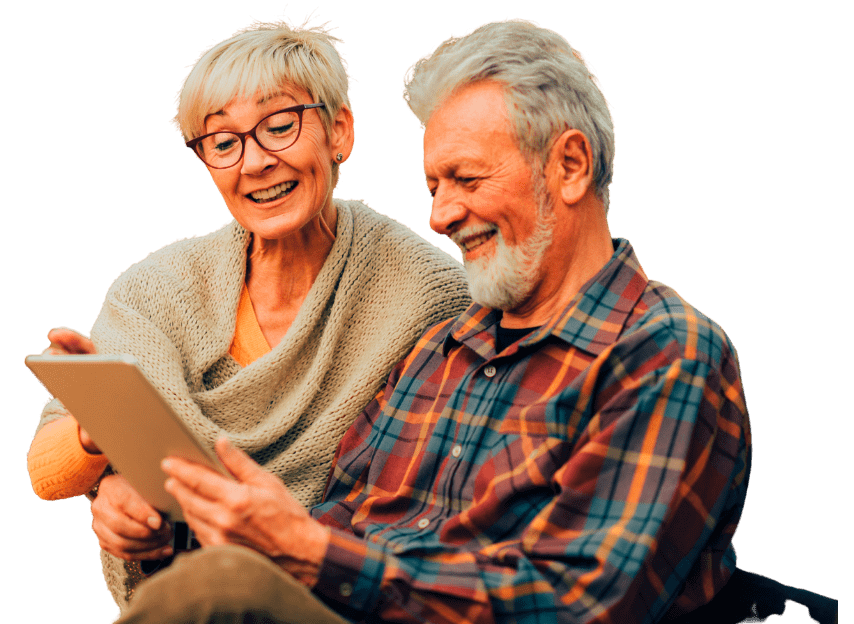 An elderly couple sitting together and engaging with a tablet, representing the transformative impact of DementiaGuard program in enhancing connectivity and enriching lives through innovative care solutions.